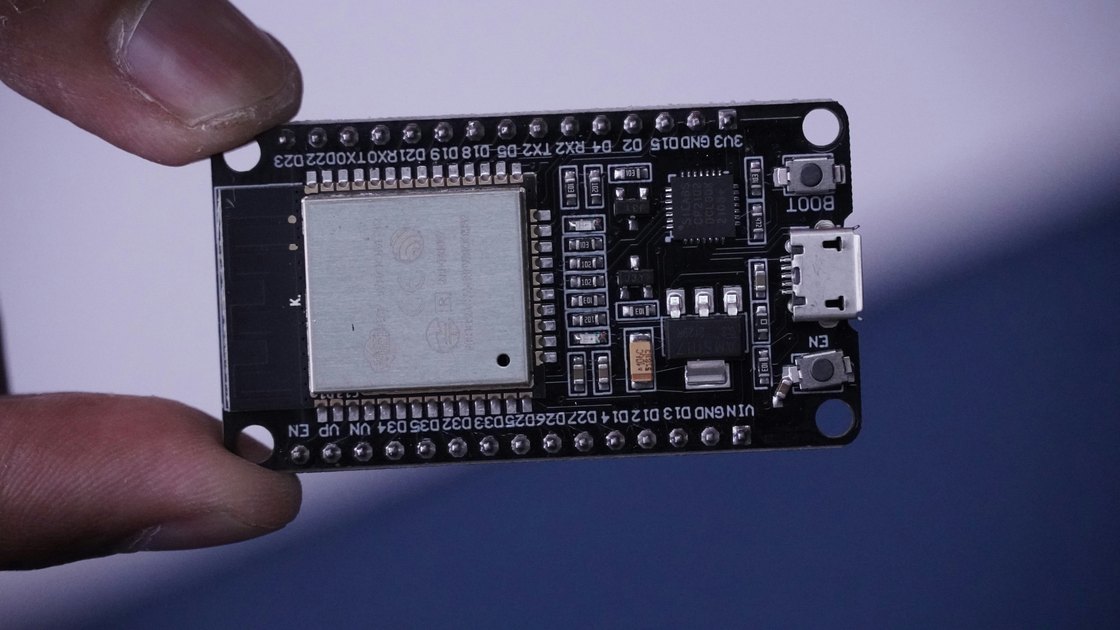 An ESP32 development board held between finger and thumb